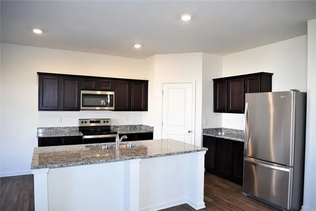 a kitchen with stainless steel appliances granite countertop a refrigerator a stove a sink a microwave and wooden cabinets