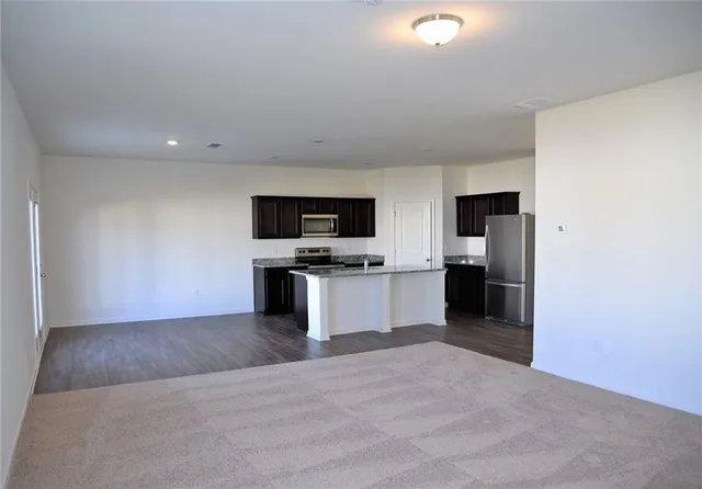 a view of kitchen with microwave a refrigerator and a stove top oven