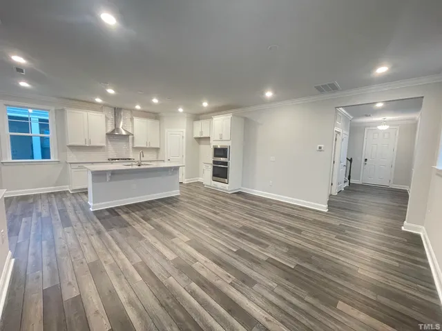 a large kitchen with kitchen island a sink dishwasher a refrigerator and wooden floor