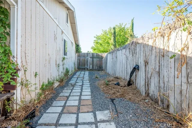 a backyard of a house with plants and trees with wooden fence