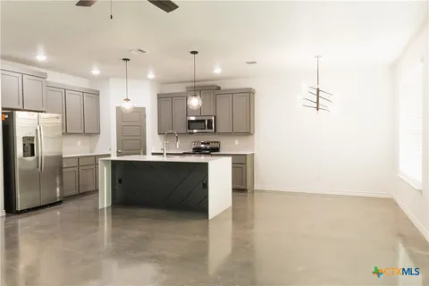a kitchen with stainless steel appliances kitchen island granite countertop a refrigerator and a stove top oven