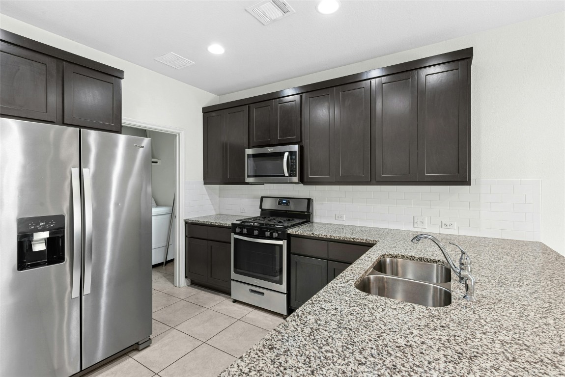 1709 Arendale Drive Leander, TX 78641 - Photo 11 of 36 a kitchen with granite countertop a refrigerator and a sink