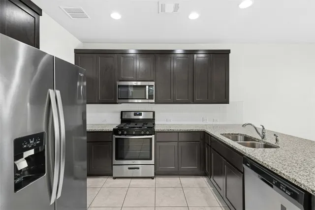 a kitchen with stainless steel appliances granite countertop a refrigerator a sink a stove a microwave and a island