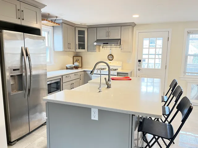 a kitchen with stainless steel appliances a sink a stove a refrigerator with white cabinets and wooden floor