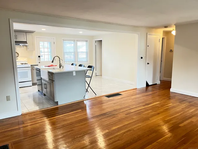 a living room with stainless steel appliances furniture and a wooden floor