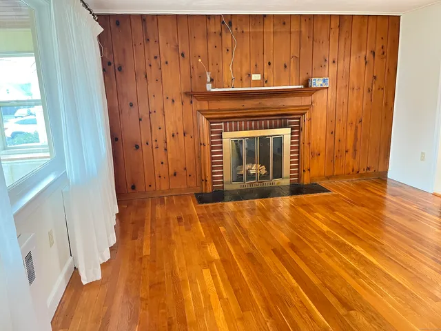 a view of an empty room with wooden floor and a fireplace