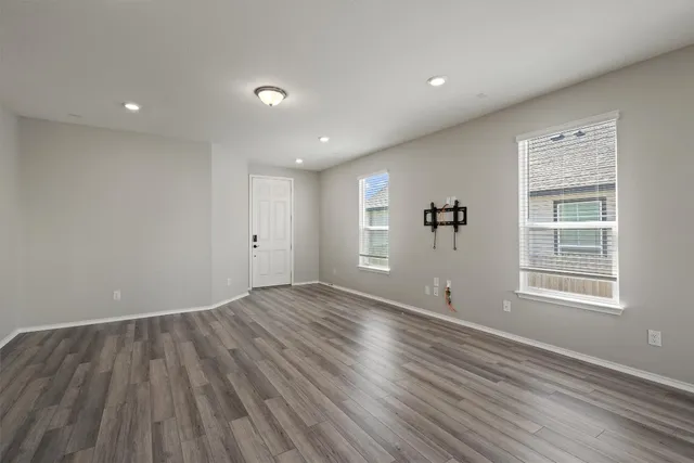 an empty room with wooden floor and windows