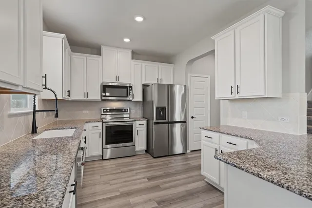 a kitchen with stainless steel appliances granite countertop a sink a stove a refrigerator and cabinets