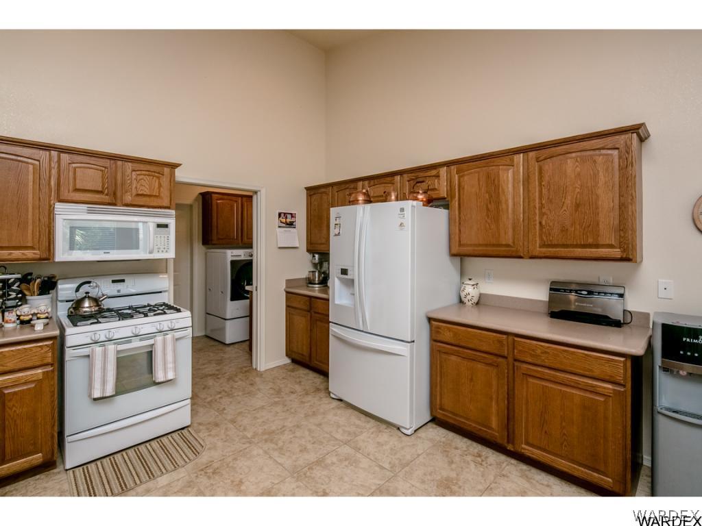 4280 East Cane Ranch Road Kingman, AZ 86401 - Photo 14 of 35 a kitchen with a refrigerator a stove top oven a washer dryer and cabinets