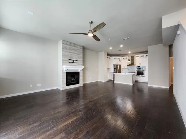 a view of a kitchen and an empty room with wooden floor fireplace