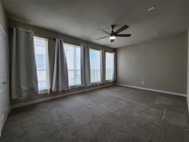 an empty room with windows and fan