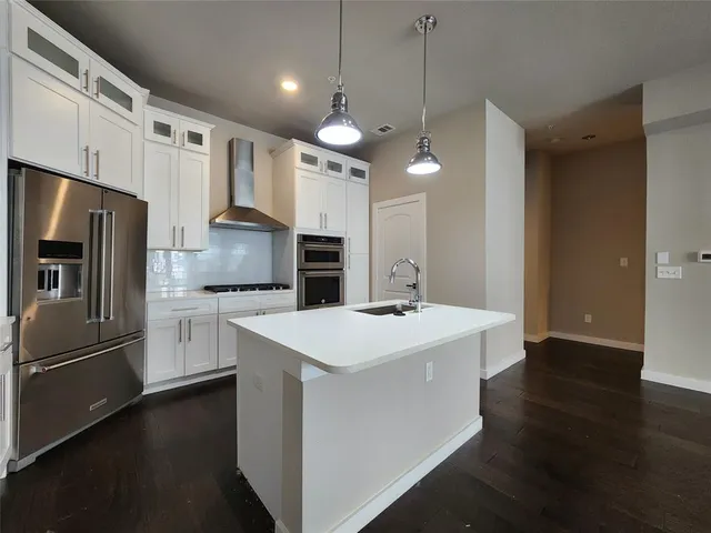a kitchen with kitchen island a sink stainless steel appliances and wooden floor