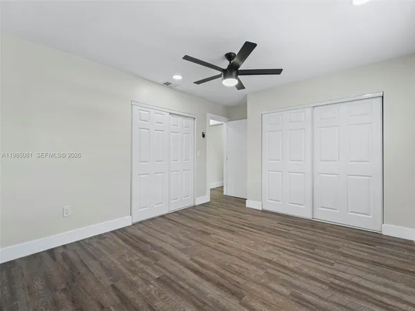 a view of empty room with wooden floor and fan