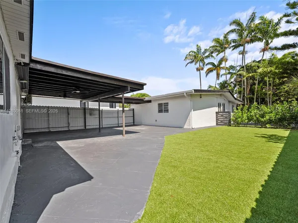 a backyard of a house with table and chairs under an umbrella