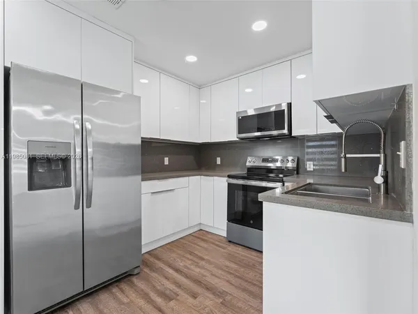 a kitchen with stainless steel appliances granite countertop a refrigerator a stove a sink and a microwave