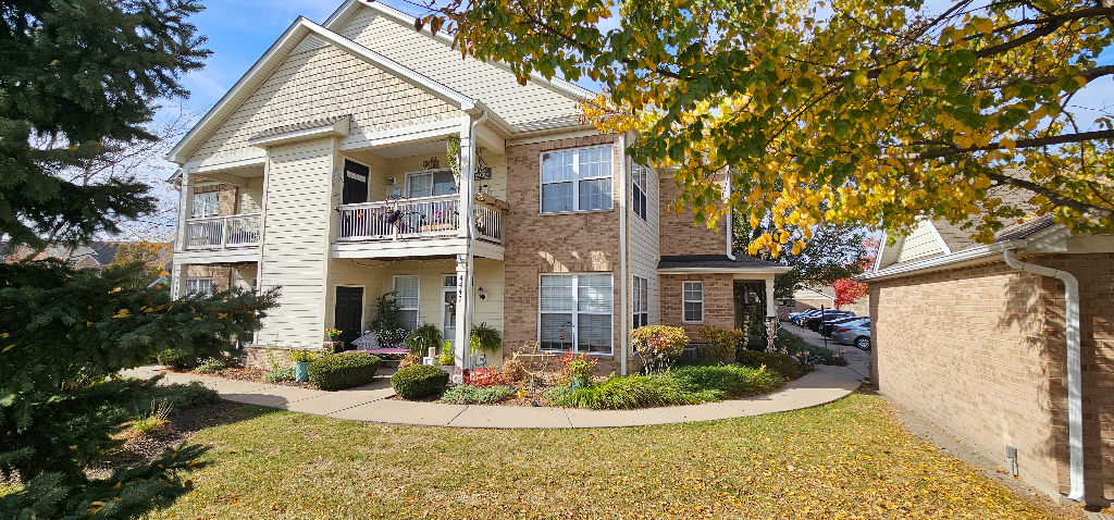 4449 Timber Ridge Court, Unit 105D Joliet, IL 60431 - Photo 1 of 4 a view of a white house with a yard and potted plants