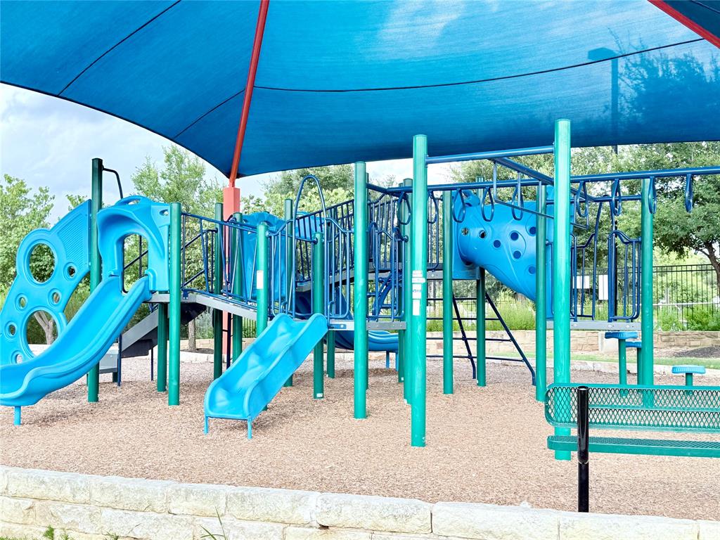 1336 Morning View Road Georgetown, TX 78628 - Photo 39 of 40 A vibrant playground features multiple slides and climbing structures, all beneath a protective shade canopy.