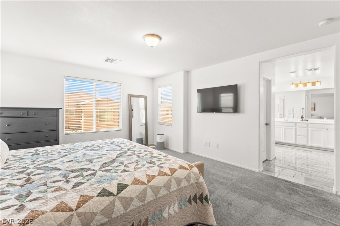 6435 Point Isabel Way Las Vegas, NV 89122 - Photo 27 of 57 Comfortable primary bedroom with soft carpet flooring and an adjacent private bathroom.