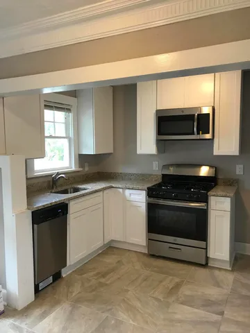 a kitchen with stainless steel appliances kitchen island granite countertop white cabinets and black appliances