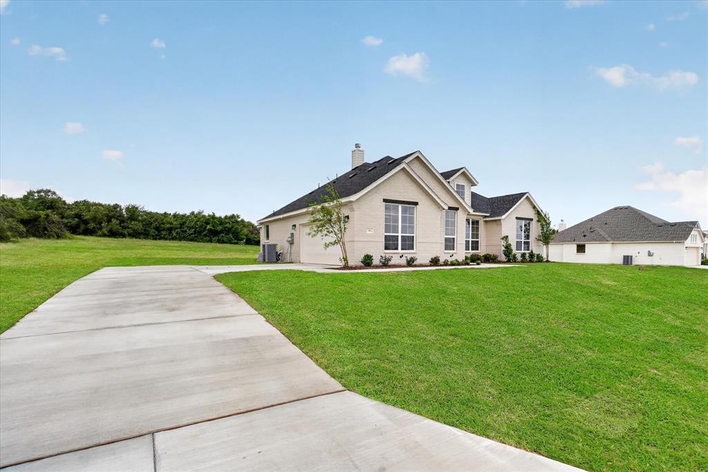 317 Skeen Peak Springtown, TX 76082 - Photo 3 of 31 Cream brick exterior featuring multiple gables and a dark shingle roof