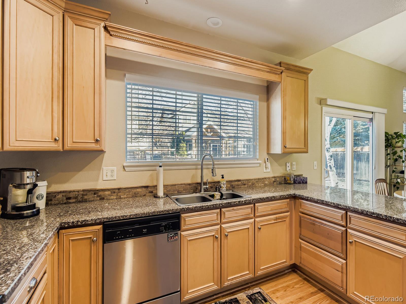 10036 Brisbane Lane Highlands Ranch, CO 80130 - Photo 8 of 27 a kitchen with granite countertop a sink window and cabinets