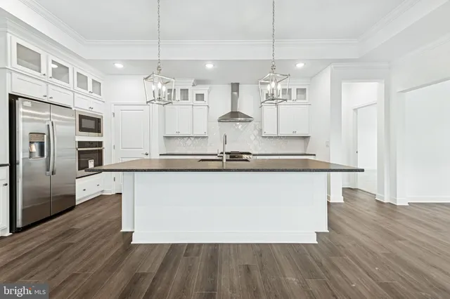 a kitchen with stainless steel appliances granite countertop a refrigerator a sink dishwasher a oven and white cabinets with wooden floor