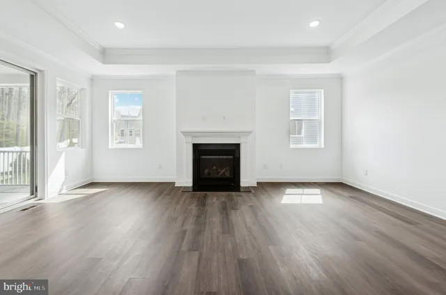 an empty room with wooden floor fireplace and windows