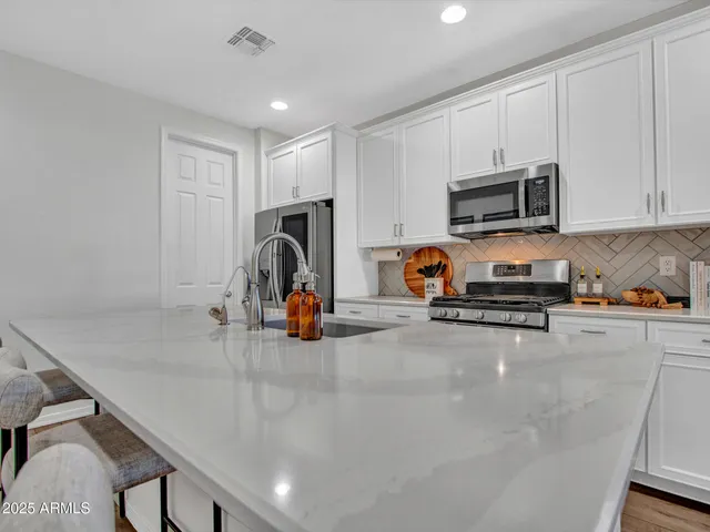 a kitchen with white cabinets sink and stainless steel appliances