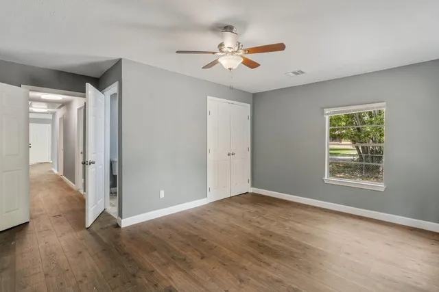 a view of an empty room with wooden floor and a window