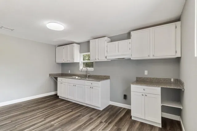 a kitchen with stainless steel appliances granite countertop a sink and cabinets with wooden floor