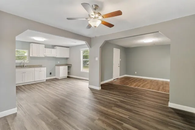 a view of empty room with wooden floor and fan