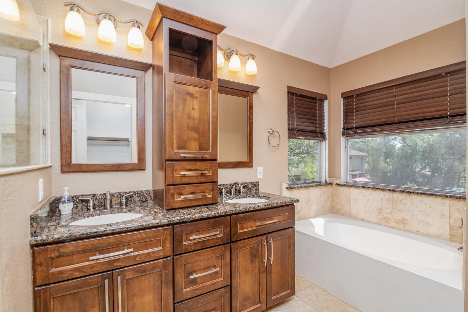 9301 Tea Rose Trail Austin, TX 78748 - Photo 22 of 36 Bathroom with double vanity, a garden tub, lofted ceiling, and light tile patterned flooring