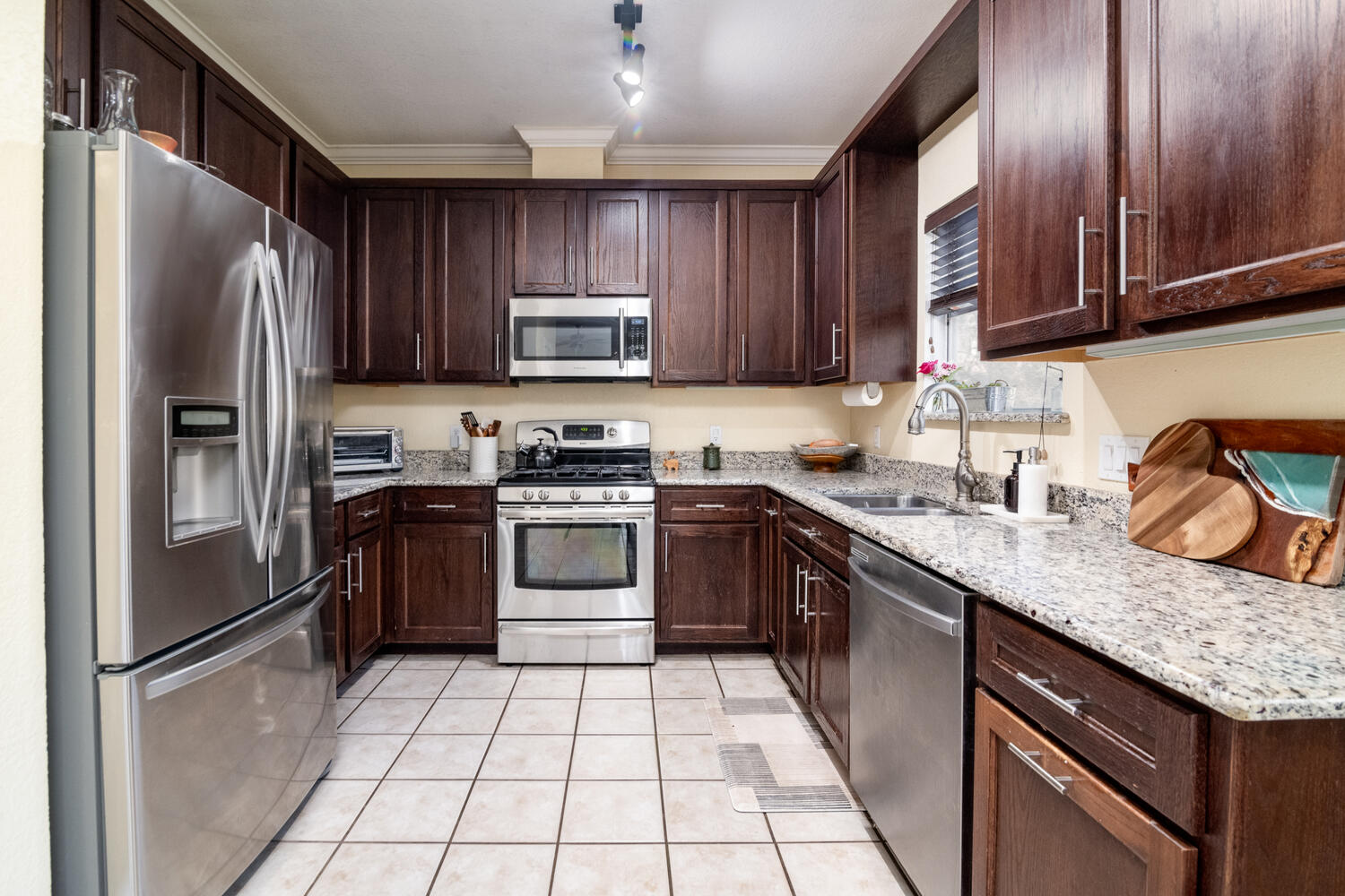 9301 Tea Rose Trail Austin, TX 78748 - Photo 10 of 36 Kitchen with stainless steel appliances, dark wood finish cabinetry, light stone countertops, and ornamental molding