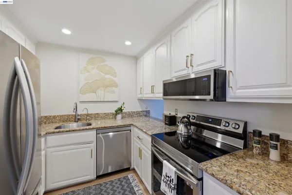 a kitchen with stainless steel appliances granite countertop a stove a sink and a microwave