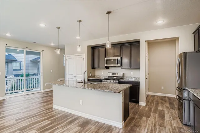 a kitchen with stainless steel appliances granite countertop a sink a stove a refrigerator cabinets and wooden floor