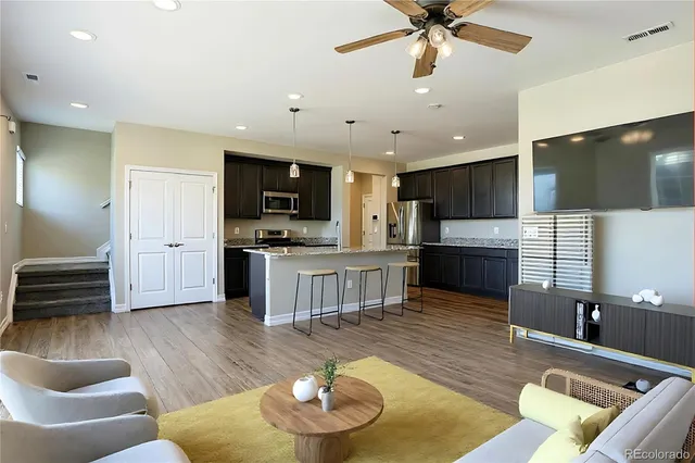 a living room with stainless steel appliances kitchen island granite countertop a living room view and a couch