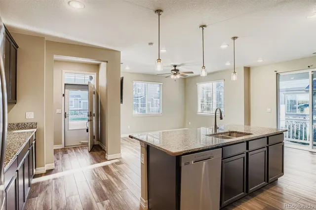 a kitchen with kitchen island granite countertop a sink refrigerator and wooden floor