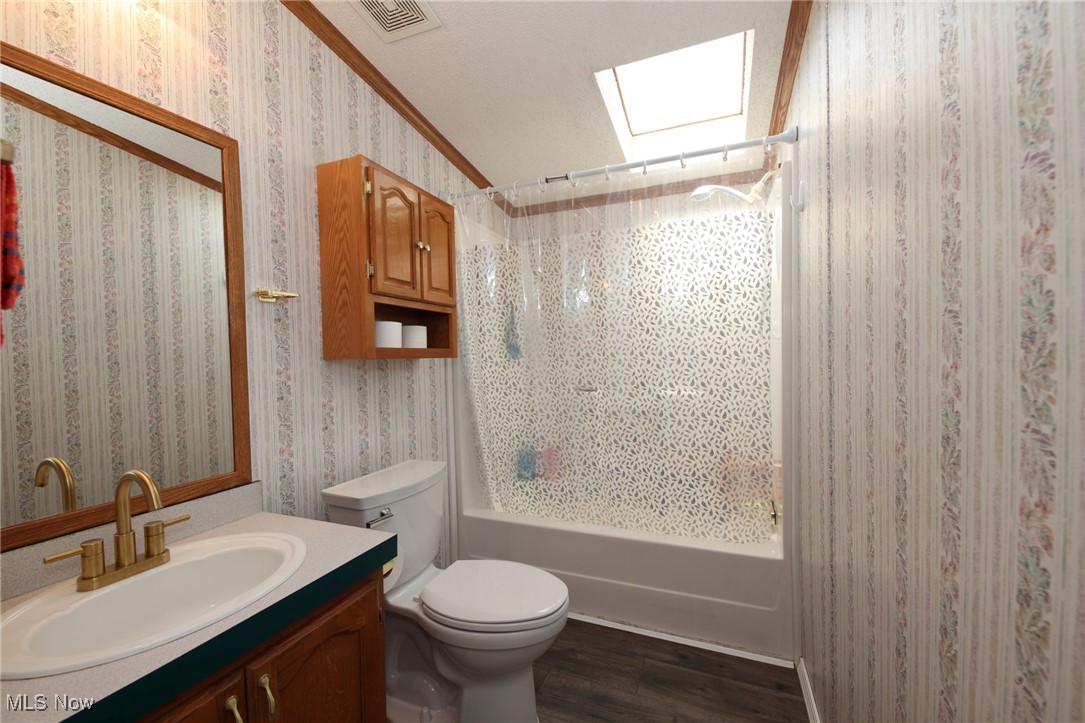 211 Gibson Road New Cumberland, WV 26047 - Photo 25 of 46 Full bathroom featuring shower / bath combo with shower curtain, wallpapered walls, a skylight, vanity, and dark wood finished floors