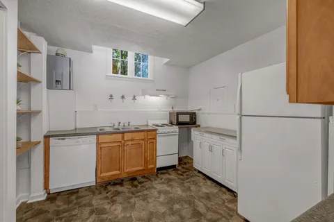 a kitchen with granite countertop cabinets a sink and white stainless steel appliances
