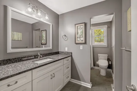 a bathroom with a granite countertop sink toilet and mirror