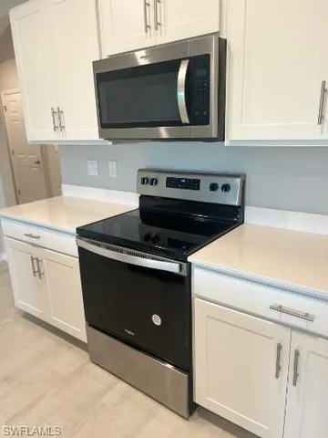 a stove top oven sitting inside of a kitchen with stainless steel appliances wooden floor