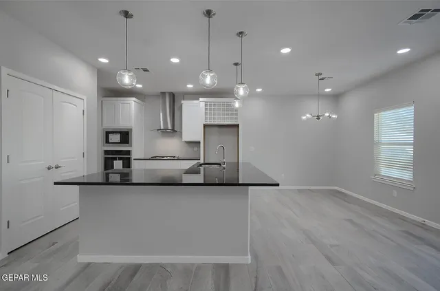 a large kitchen with stainless steel appliances a large counter top a stove and a sink