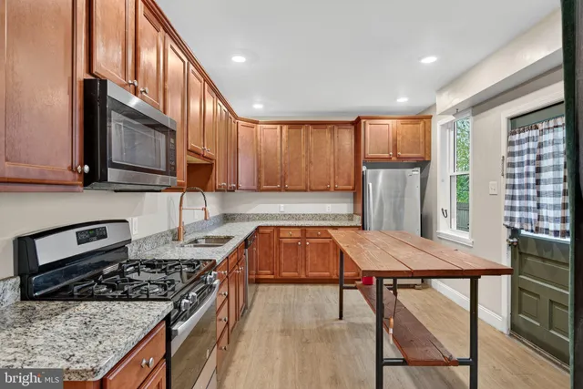 a kitchen with granite countertop wooden cabinets a dining table and chairs