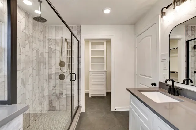 a bathroom with a granite countertop sink a mirror and shower