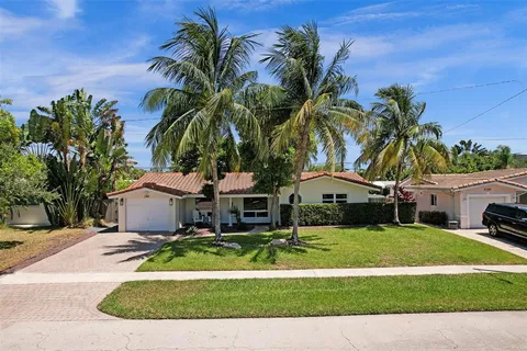 a front view of a house with garden and trees