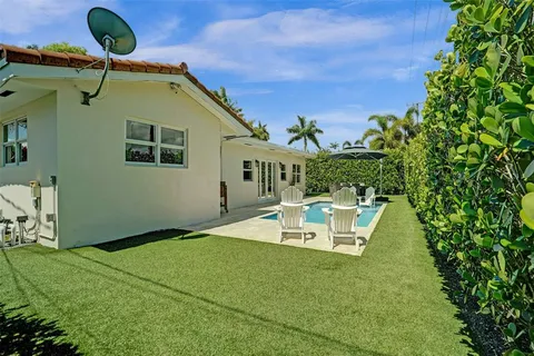 a view of a house with a big yard and palm trees