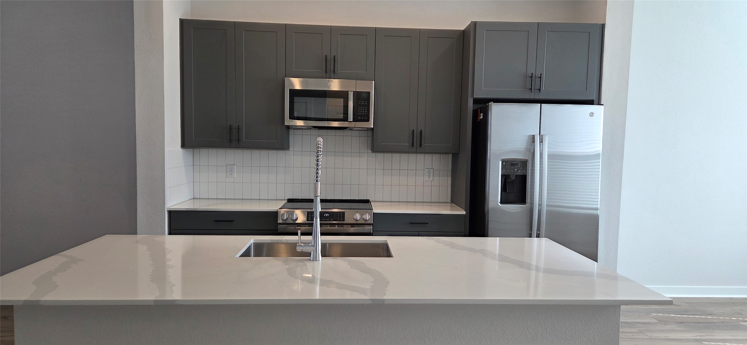8107 Wilder Road Austin, TX 78736 - Photo 4 of 35 A contemporary kitchen features sleek gray cabinetry and an expansive island with a stainless steel sink.