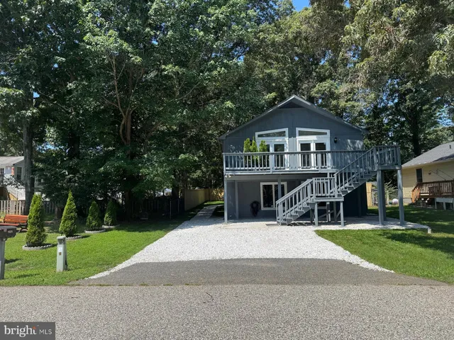 a view of house with a yard and large trees