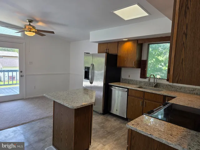 a kitchen with stainless steel appliances granite countertop a sink and a refrigerator