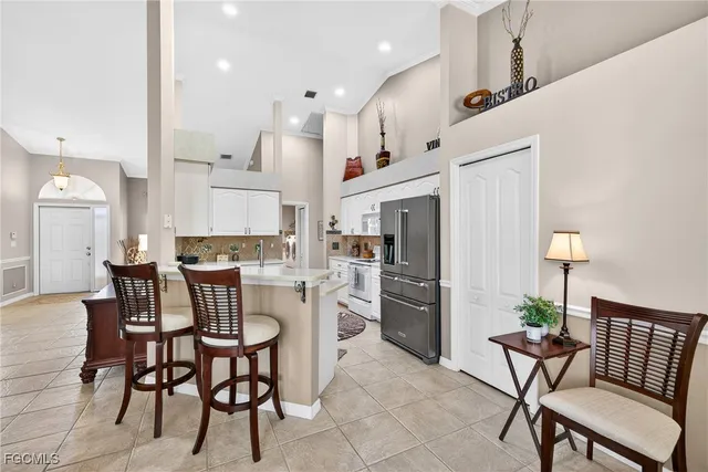 a kitchen with stainless steel appliances kitchen island granite countertop a dining table chairs and a refrigerator